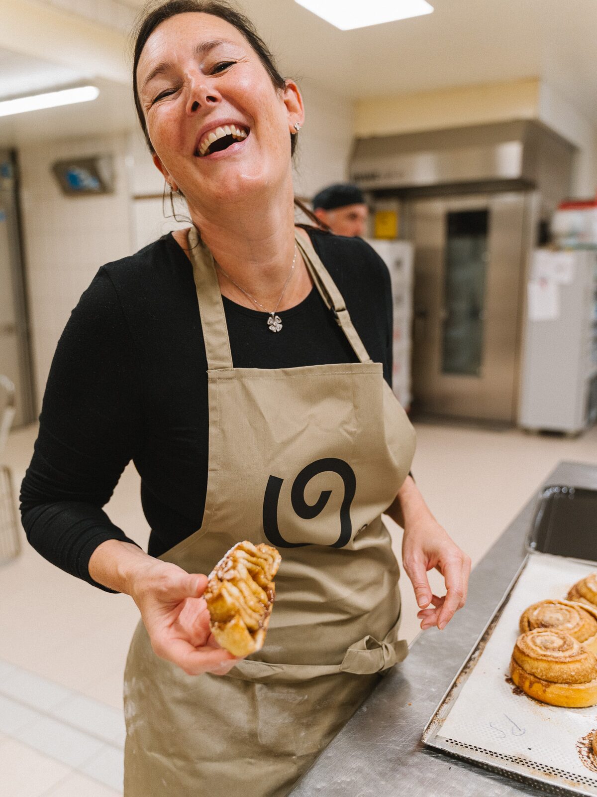 Lachen in der Produktion, eine frische Zimtschnecke in der Hand
