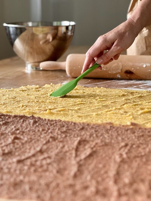 Der Teig wird von Hand mit Butter bestrichen